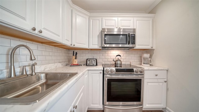 kitchen with decorative backsplash, stainless steel appliances, white cabinetry, and sink