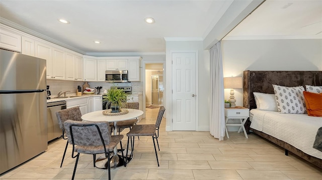 kitchen with white cabinets, decorative backsplash, crown molding, and stainless steel appliances