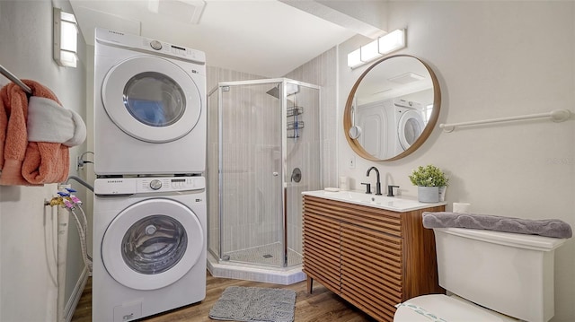 clothes washing area with hardwood / wood-style flooring, stacked washer / drying machine, and sink