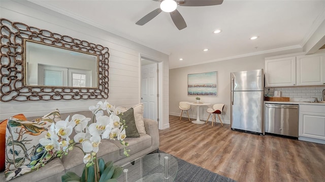 living room with ceiling fan, sink, light hardwood / wood-style floors, and ornamental molding