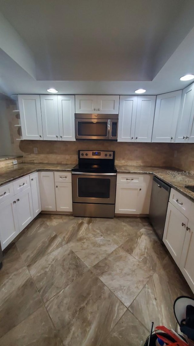 kitchen with white cabinets, decorative backsplash, and stainless steel appliances