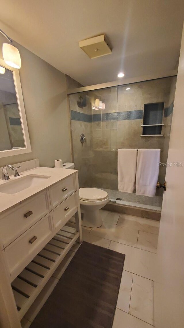 bathroom featuring tile patterned floors, a shower with door, vanity, and toilet