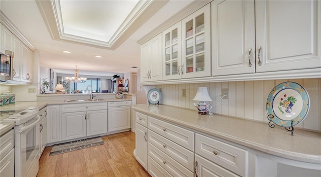 kitchen with white appliances, sink, hanging light fixtures, light wood-type flooring, and white cabinetry