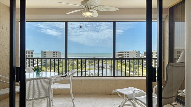 sunroom featuring ceiling fan and a water view