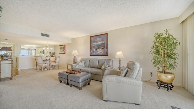 living room with a notable chandelier, light colored carpet, and a textured ceiling