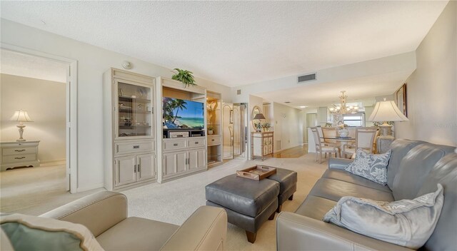 living room featuring light colored carpet, a textured ceiling, and an inviting chandelier