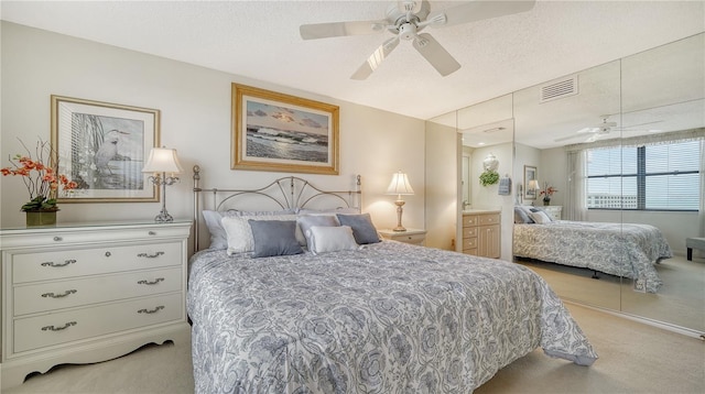 carpeted bedroom featuring ceiling fan and a textured ceiling