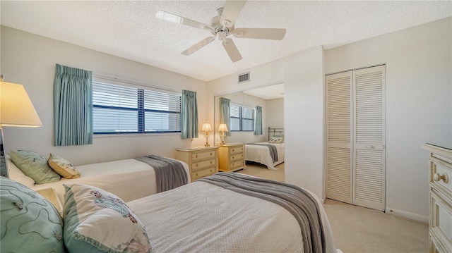 bedroom featuring light carpet, a textured ceiling, a closet, and ceiling fan