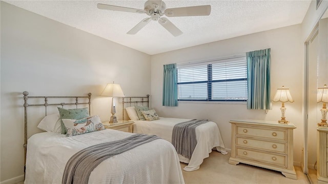 bedroom with ceiling fan, light carpet, and a textured ceiling