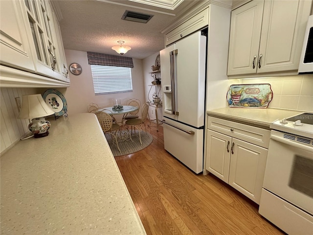 kitchen with visible vents, white appliances, light wood-style floors, light countertops, and white cabinets