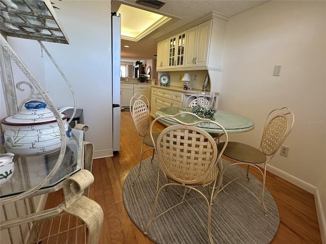 dining space with baseboards, washer / dryer, wood finished floors, and visible vents