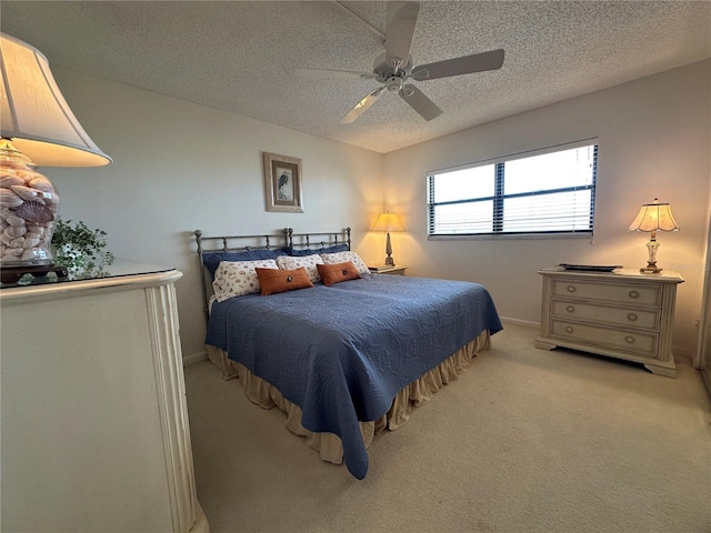 bedroom with a ceiling fan, a textured ceiling, light carpet, and baseboards