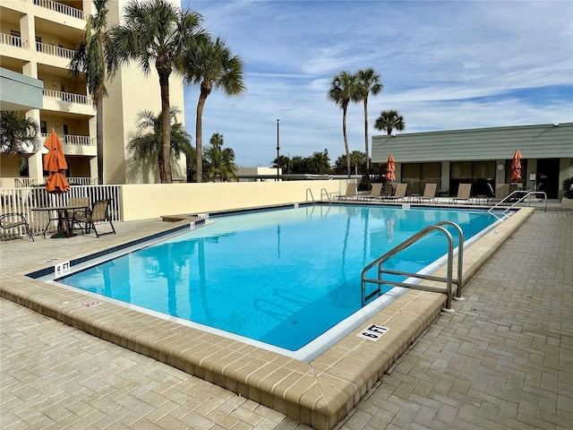 community pool with fence and a patio area
