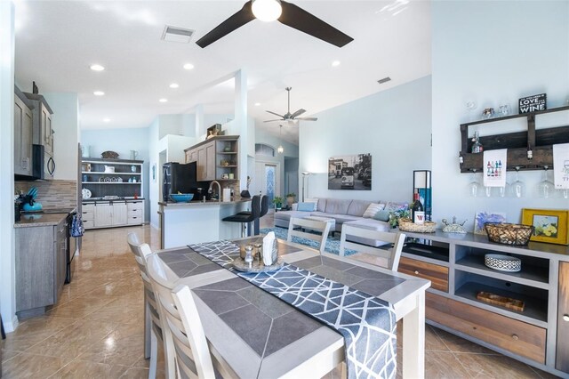 kitchen featuring sink, stainless steel appliances, high vaulted ceiling, kitchen peninsula, and decorative backsplash