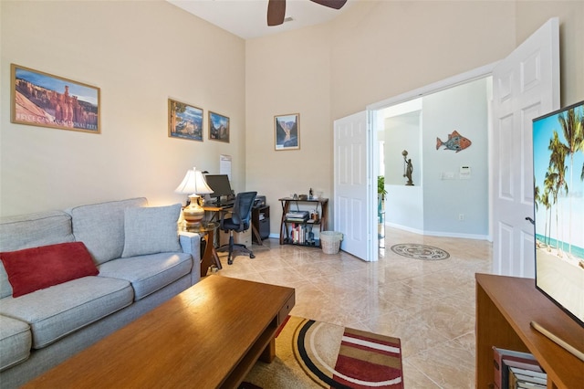 living room with ceiling fan and a towering ceiling