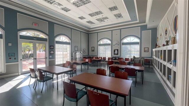 dining space with plenty of natural light, a raised ceiling, a towering ceiling, and french doors