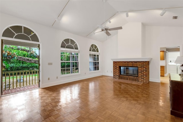 unfurnished living room with a brick fireplace, track lighting, high vaulted ceiling, and ceiling fan