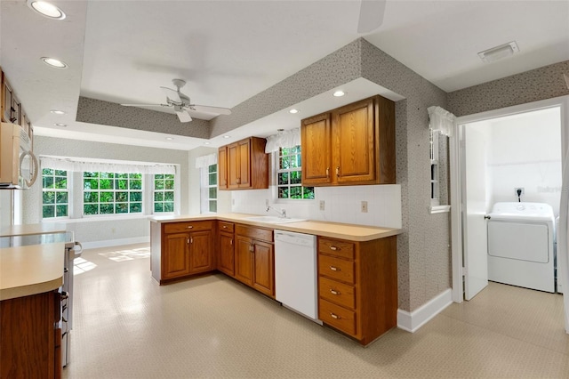 kitchen featuring kitchen peninsula, white appliances, ceiling fan, sink, and washer / clothes dryer