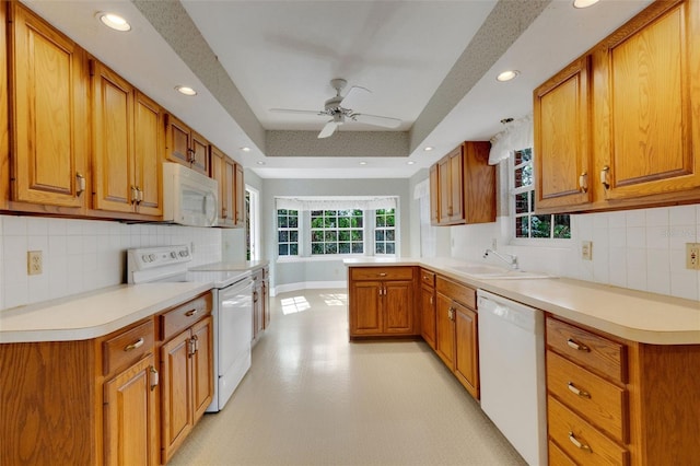 kitchen featuring plenty of natural light, sink, white appliances, and kitchen peninsula