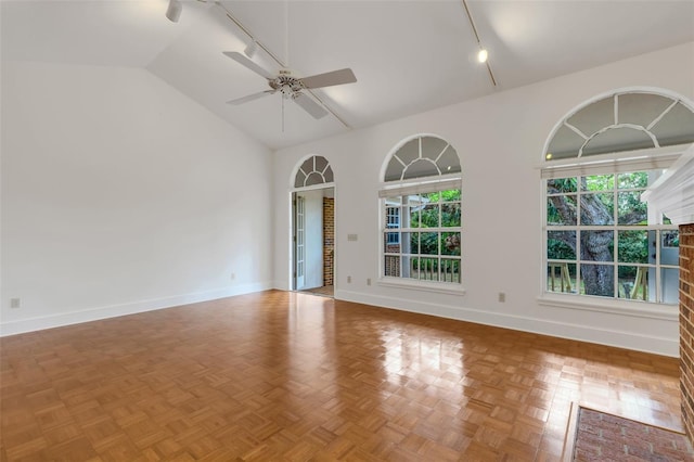 spare room featuring rail lighting, a brick fireplace, light parquet floors, ceiling fan, and high vaulted ceiling