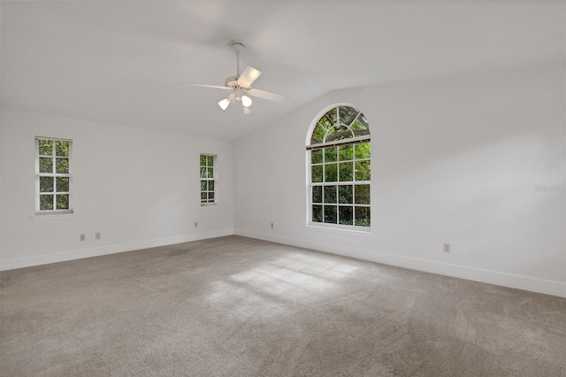 carpeted empty room with ceiling fan, a healthy amount of sunlight, and lofted ceiling