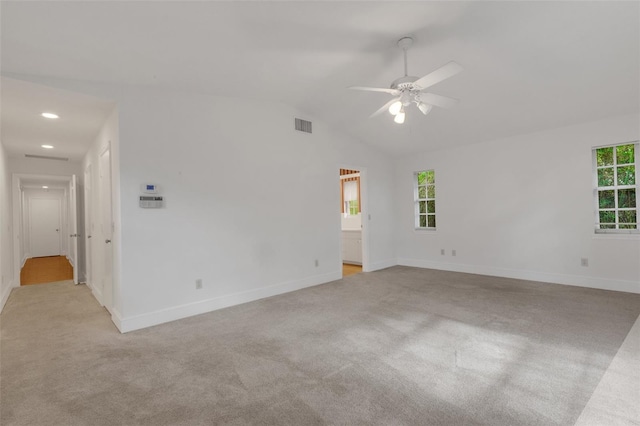 carpeted empty room with vaulted ceiling, ceiling fan, and a healthy amount of sunlight