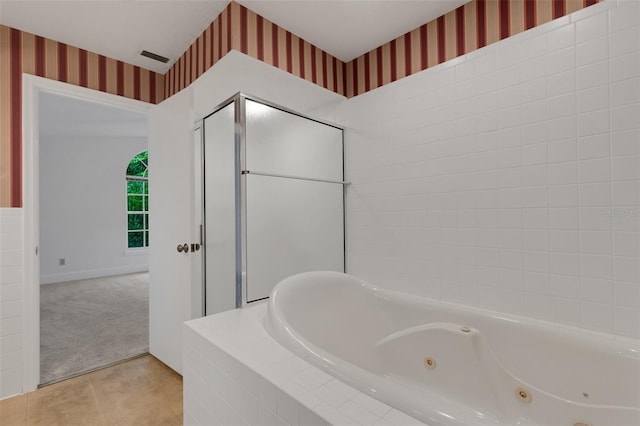 bathroom with tile patterned flooring and tiled tub