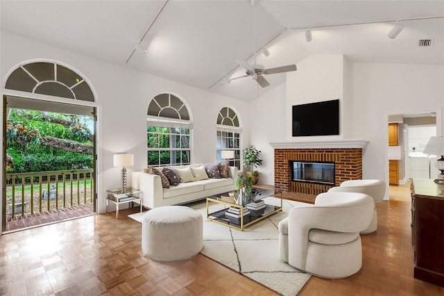 living room with rail lighting, a brick fireplace, parquet floors, ceiling fan, and high vaulted ceiling