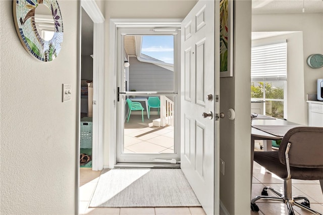 doorway with a healthy amount of sunlight and light tile patterned floors