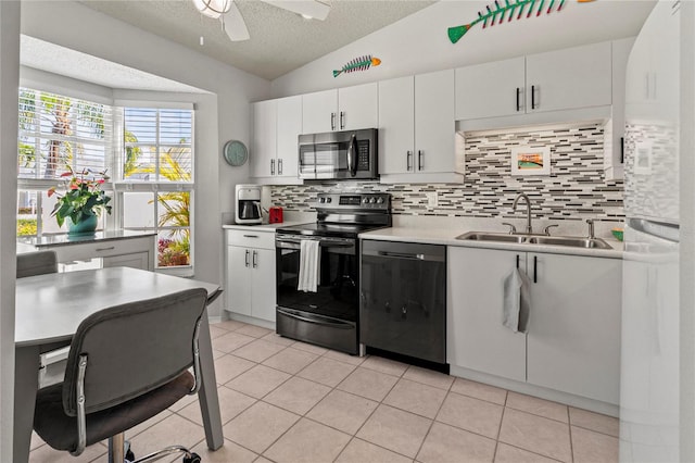 kitchen with white cabinetry, sink, stainless steel appliances, a textured ceiling, and lofted ceiling