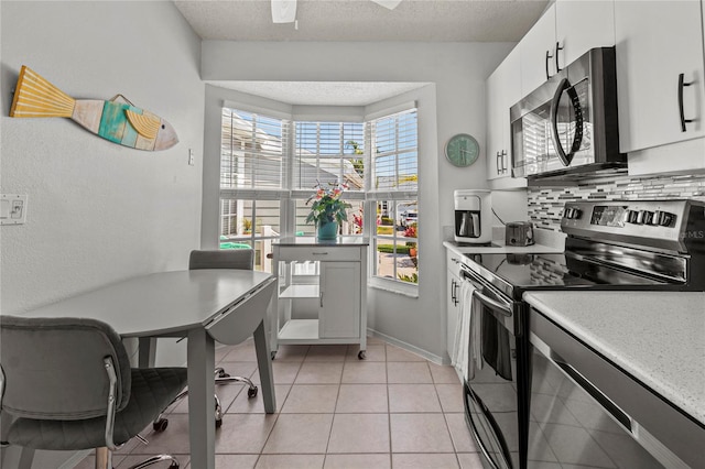 kitchen with light tile patterned floors, a textured ceiling, tasteful backsplash, white cabinetry, and stainless steel appliances