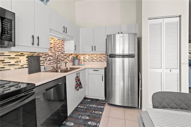 kitchen featuring sink, light tile patterned floors, tasteful backsplash, white cabinets, and black appliances