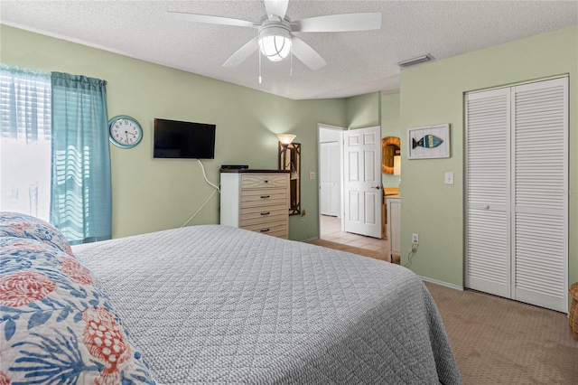 carpeted bedroom with ceiling fan, a closet, and a textured ceiling