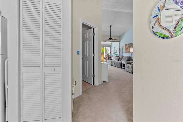 corridor featuring light colored carpet and a textured ceiling