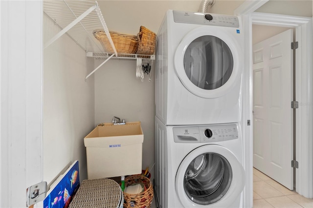 laundry room featuring stacked washer / dryer, sink, and light tile patterned flooring