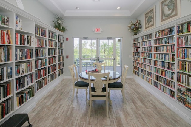 interior space featuring a raised ceiling, light wood-type flooring, and ornamental molding