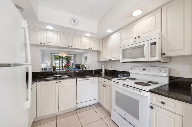 kitchen featuring white appliances, sink, light tile patterned floors, a textured ceiling, and white cabinetry