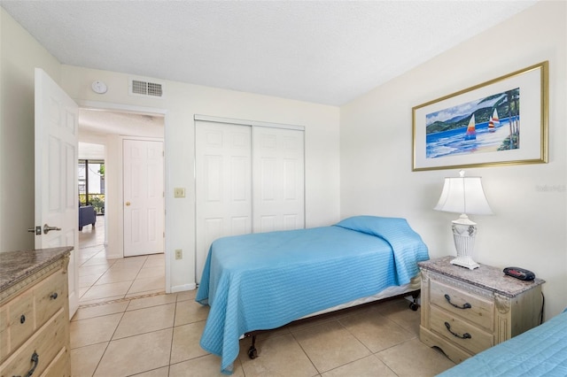 tiled bedroom with a closet and a textured ceiling