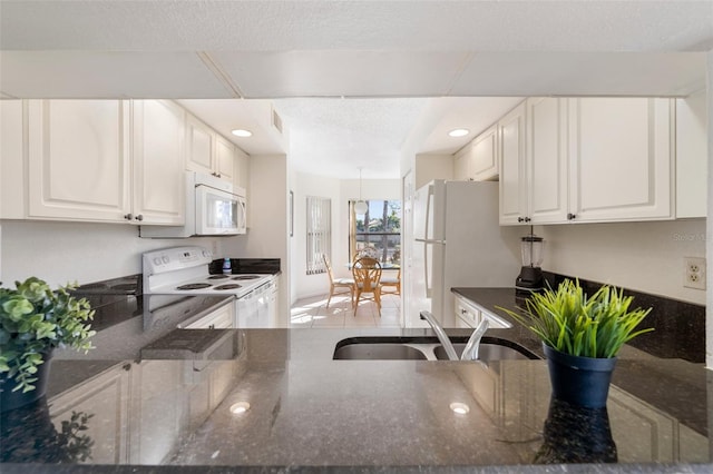 kitchen featuring white cabinets, white appliances, sink, and dark stone counters