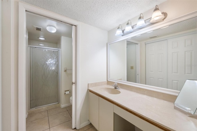 bathroom with tile patterned flooring, vanity, toilet, and walk in shower