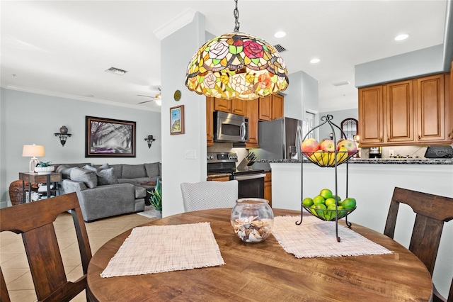 tiled dining room with ceiling fan and ornamental molding