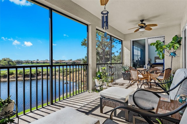 sunroom / solarium with ceiling fan and a water view