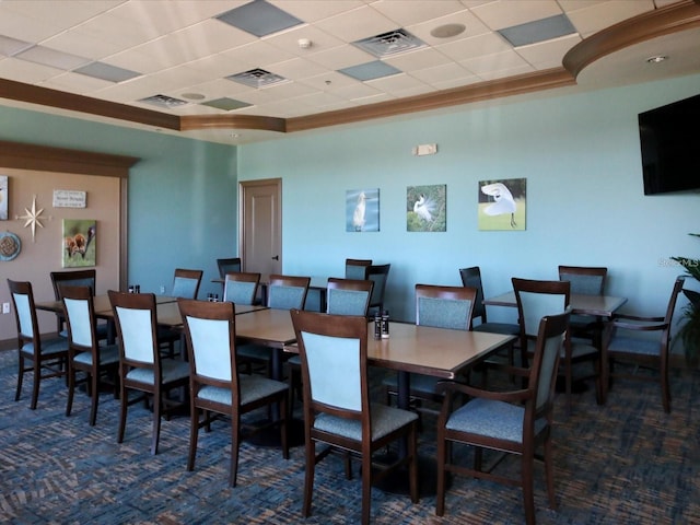 carpeted dining space with ornamental molding and a drop ceiling