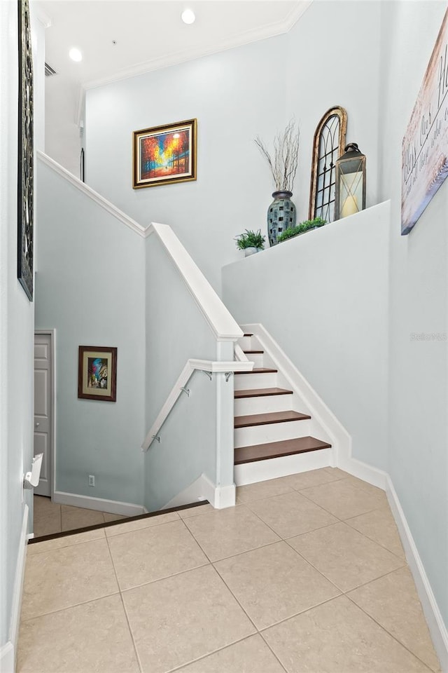 stairs featuring a high ceiling, ornamental molding, and tile patterned floors