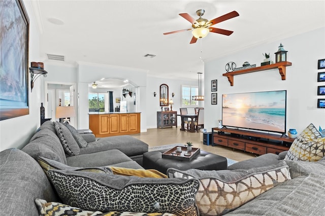 living room with light tile patterned floors, crown molding, and ceiling fan