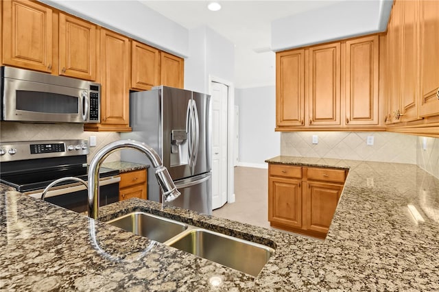 kitchen featuring appliances with stainless steel finishes, stone countertops, sink, and backsplash