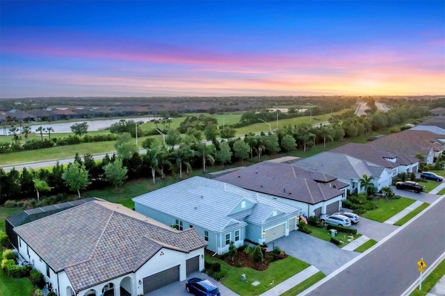 aerial view at dusk featuring a water view