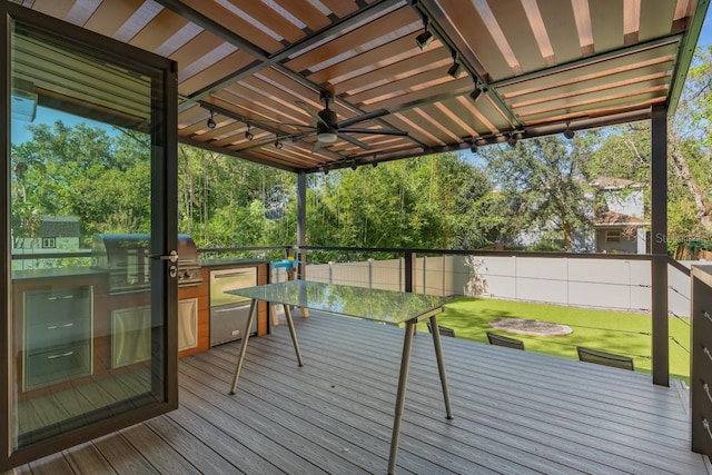 wooden deck featuring area for grilling, ceiling fan, a yard, and exterior kitchen