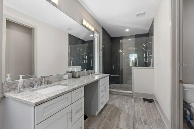 bathroom with vanity, hardwood / wood-style flooring, toilet, walk in shower, and a textured ceiling