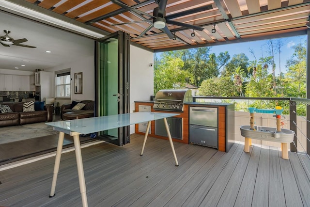 deck featuring area for grilling, ceiling fan, and exterior kitchen